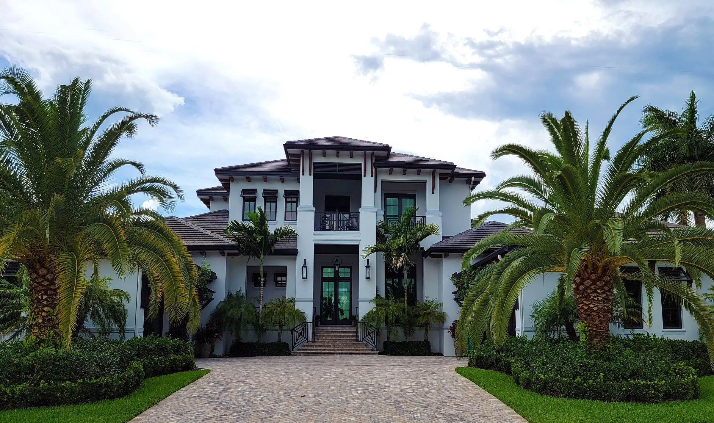 Palm-lined estate entry with paver driveway