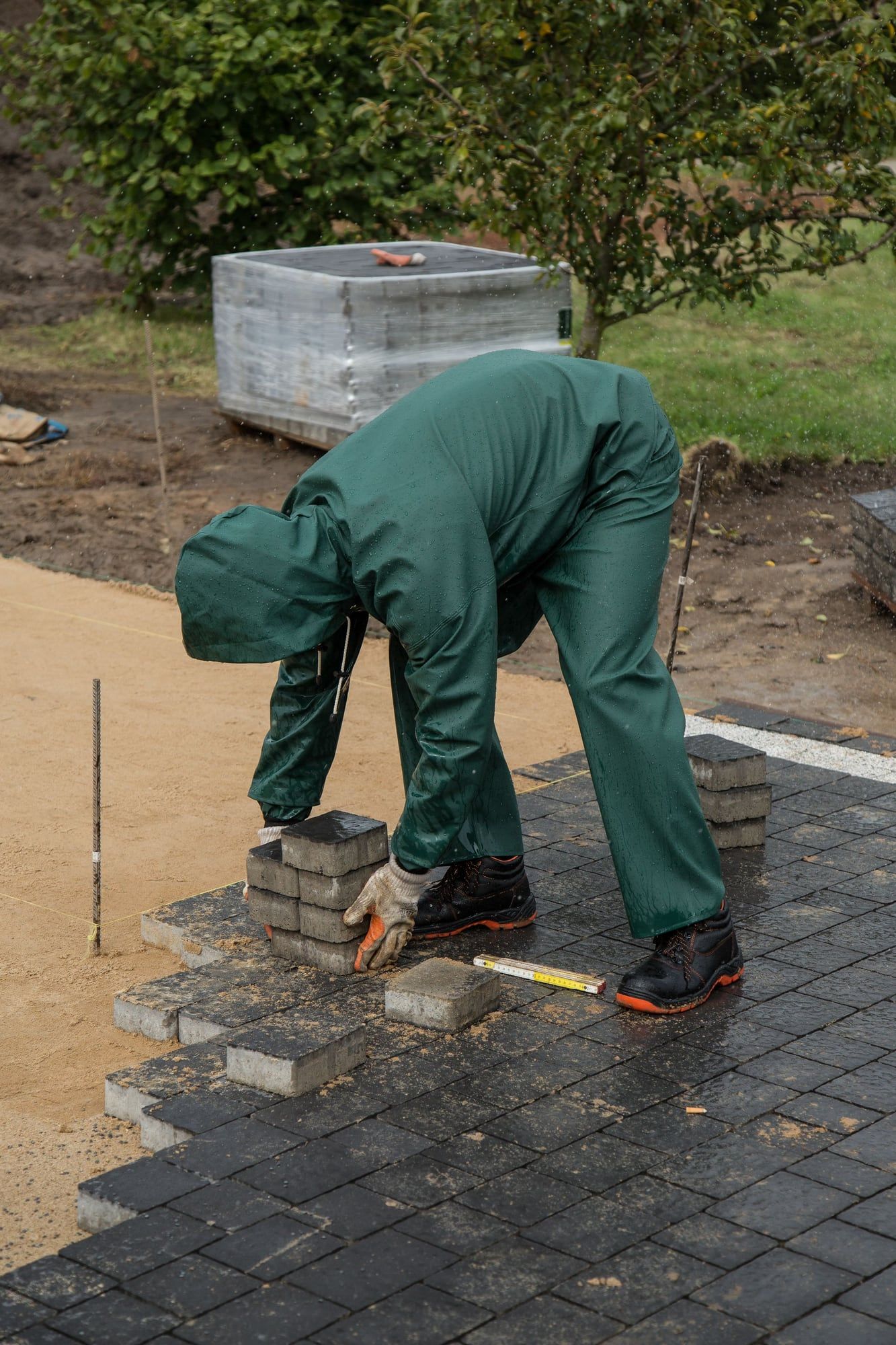 Installer laying interlocking pavers on a compacted base